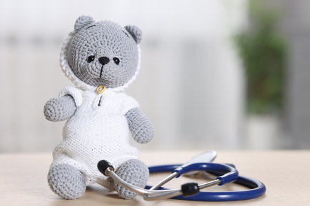 Pediatrics concept. Toy bear with stethoscope on table indoors, space for textの写真素材