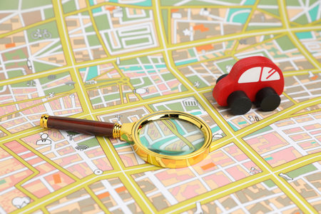 Red toy car and magnifying glass on city map. Road tripの写真素材
