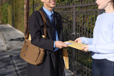 Postman giving parcel to woman outdoors, closeupの写真素材