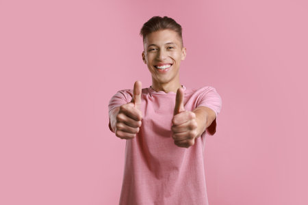 Happy man showing thumbs up on pink background. Like gestureの写真素材
