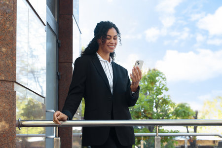 Portrait of young woman with phone wearing stylish suit outdoorsの写真素材