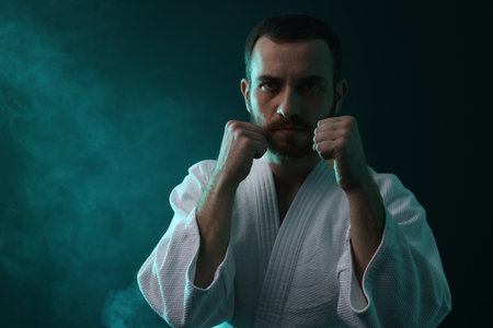 Karate fighter wearing uniform in color lights and smoke