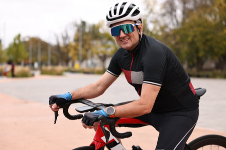 Athletic man with helmet and bicycle outdoors
