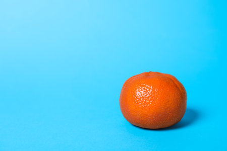 Fresh ripe tangerine on light blue background. Space for textの写真素材