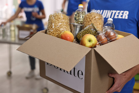 Volunteer holding donation box with food products indoors, closeupの写真素材