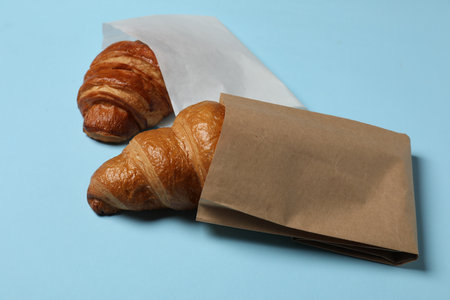 Paper bags with fresh croissants on light blue backgroundの写真素材