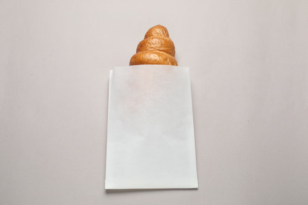 Paper bag with fresh croissant on beige background, top viewの写真素材