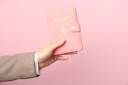 Woman holding passport in bright cover on pink background, closeupの写真素材