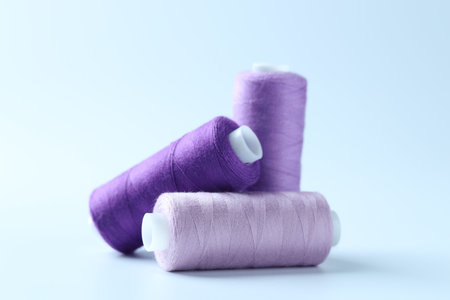Spools of colorful sewing threads on light background, closeup