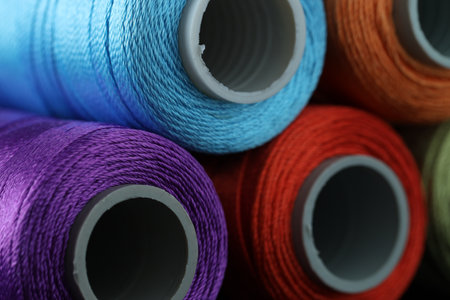 Spools of colorful sewing threads as background, closeup