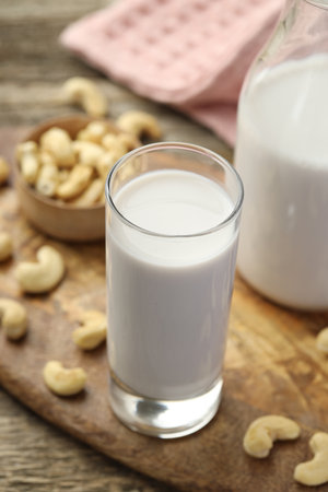 Fresh cashew milk in glass and nuts on wooden table, closeupの写真素材