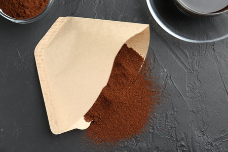 Paper filter, ground coffee and cup of drink on black table, flat layの写真素材