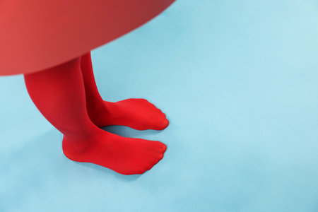 Young woman in red tights posing on light blue background, closeup. Space for textの写真素材