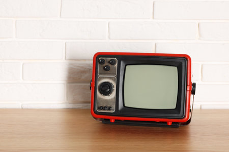 Retro tv set on wooden shelf against white brick wall. Space for textの写真素材