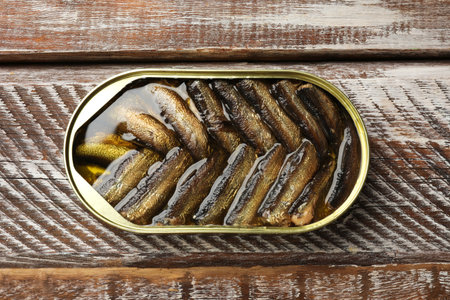 Tasty sprats in tin can on wooden table, top viewの写真素材