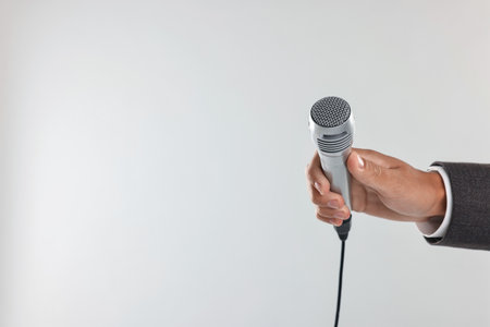 Man with microphone on light grey background, closeup. Space for textの写真素材