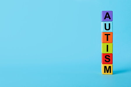Word Autism made of colorful cubes on light blue background, space for text