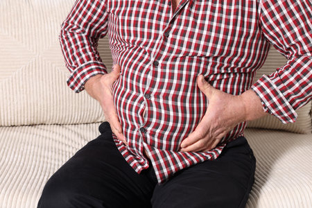 Overweight man in tight shirt on sofa indoors, closeupの写真素材