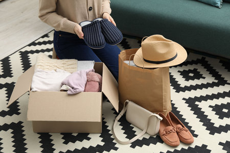 Woman with used clothes on floor indoors, closeup