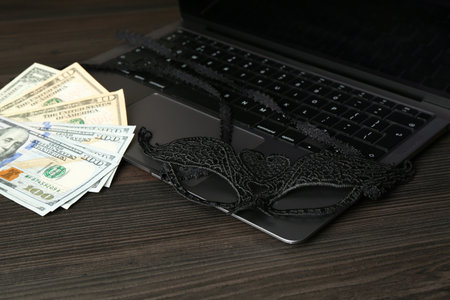 Laptop, mask and money on wooden surface, closeupの写真素材