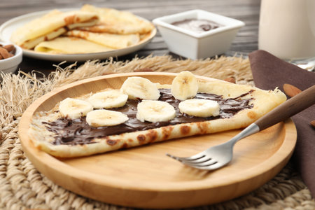 Delicious crepe with chocolate paste and banana served on table, closeupの写真素材