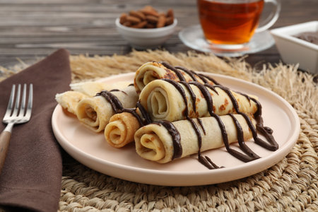 Delicious crepes with chocolate sauce served on wooden tableの写真素材