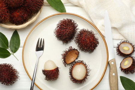 Delicious ripe rambutans served on white wooden table, flat layの写真素材
