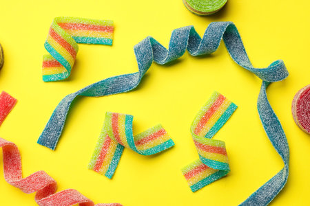 Different tasty sour belts on yellow background, flat layの写真素材