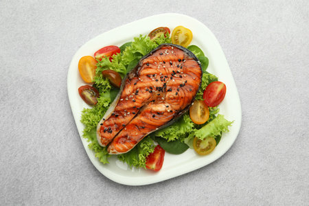 Tasty grilled salmon steak and vegetables on light grey table, top viewの写真素材
