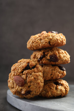 Delicious oatmeal cookies with raisins and nuts on grey table, closeup