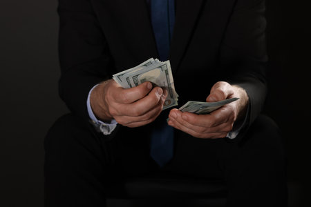 Man holding dollar banknotes on black background, closeupの写真素材