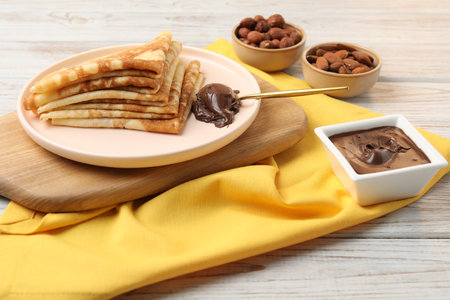 Delicious crepes with chocolate paste and nuts on wooden table, closeupの写真素材