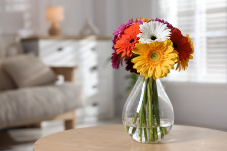 Bouquet of beautiful gerbera flowers in glass vase on wooden table indoors, space for textの写真素材