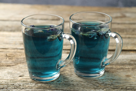 Delicious butterfly pea flower tea in cups on wooden tableの写真素材