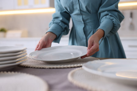 Woman setting table for dinner at home, closeup