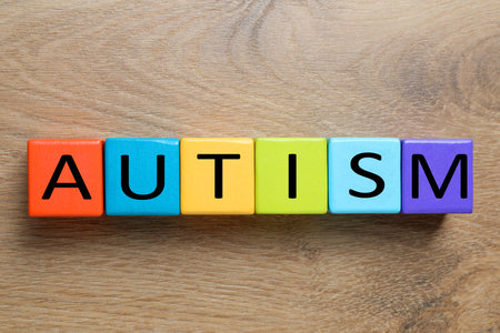 Word Autism made of colorful cubes on wooden background, top viewの写真素材