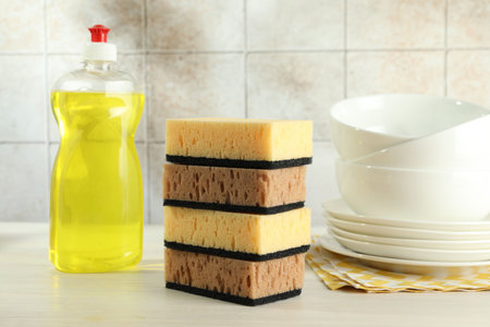 Stack of sponges, detergent and dishware on light wooden table, closeupの写真素材