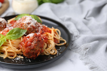 Delicious pasta with meatballs, basil and cheese on white table, closeupの写真素材