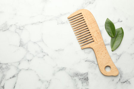 Wooden comb and leaves on white marble table, flat lay. Space for textの写真素材