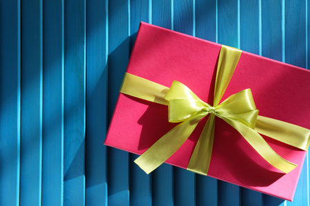 Gift box with bow on blue textured table, top view. Space for textの写真素材