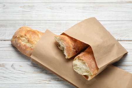 Paper bags with fresh baguettes on wooden table, top viewの写真素材