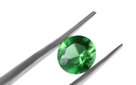 Tweezers with shiny green gemstone isolated on white