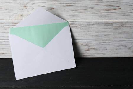 Paper envelope with letter on black wooden table. Mockup for designの写真素材
