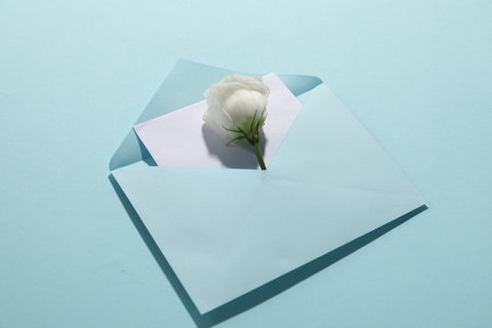 Paper envelope with letter and flower on light blue background, closeup. Mockup for designの写真素材