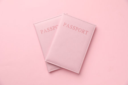 Passports in color covers on pink background, top viewの写真素材