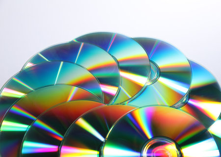 Many shiny compact discs on light background