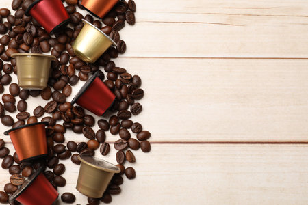 Coffee capsules and beans on light wooden table, flat lay. Space for textの写真素材
