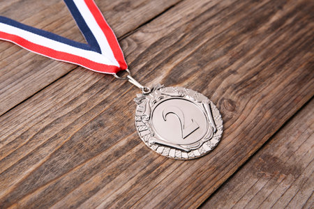 Silver medal with striped ribbon on wooden background, closeupの写真素材
