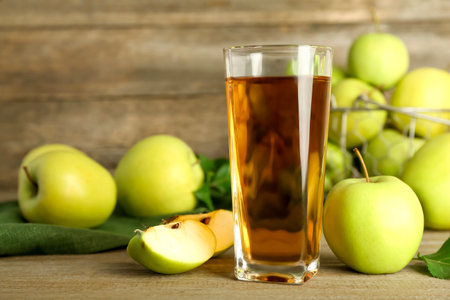 Glass of juice and apples on wooden tableの写真素材