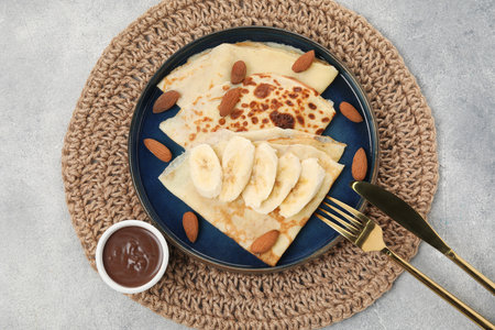 Delicious crepes with banana and almonds served on grey table, top viewの写真素材